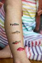 Colorful fish tattoos on a person's arm with a striped background