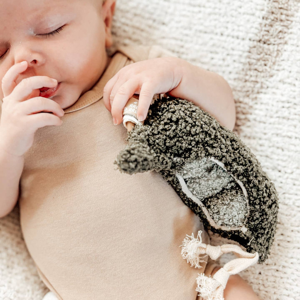 Baby wearing a brown outfit with a textured legging on a soft, beige background