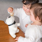 Two children playing with a plush dog toy on a wooden table.
