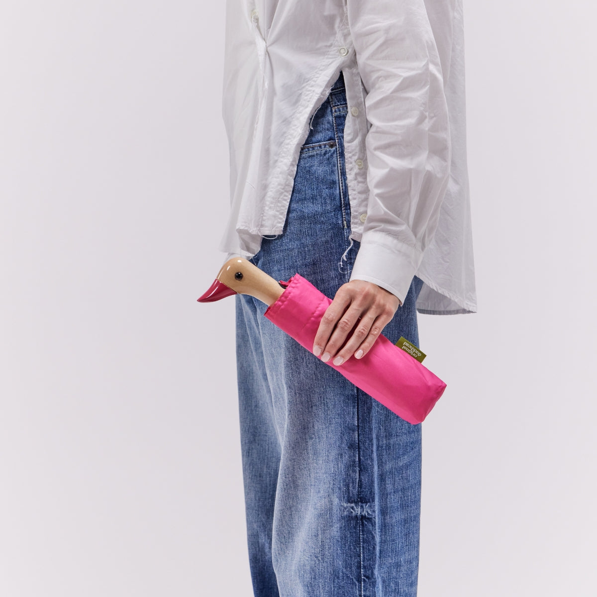 Person holding a pink umbrella with a duck design against a plain background