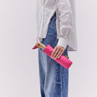 Person holding a pink umbrella with a duck design against a plain background