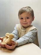 Child holding a teddy bear against a plain background