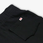 Black pants with a red and white logo on the pocket against a white background