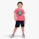 Child wearing a pink t-shirt with a tiger graphic and black shorts on a white background