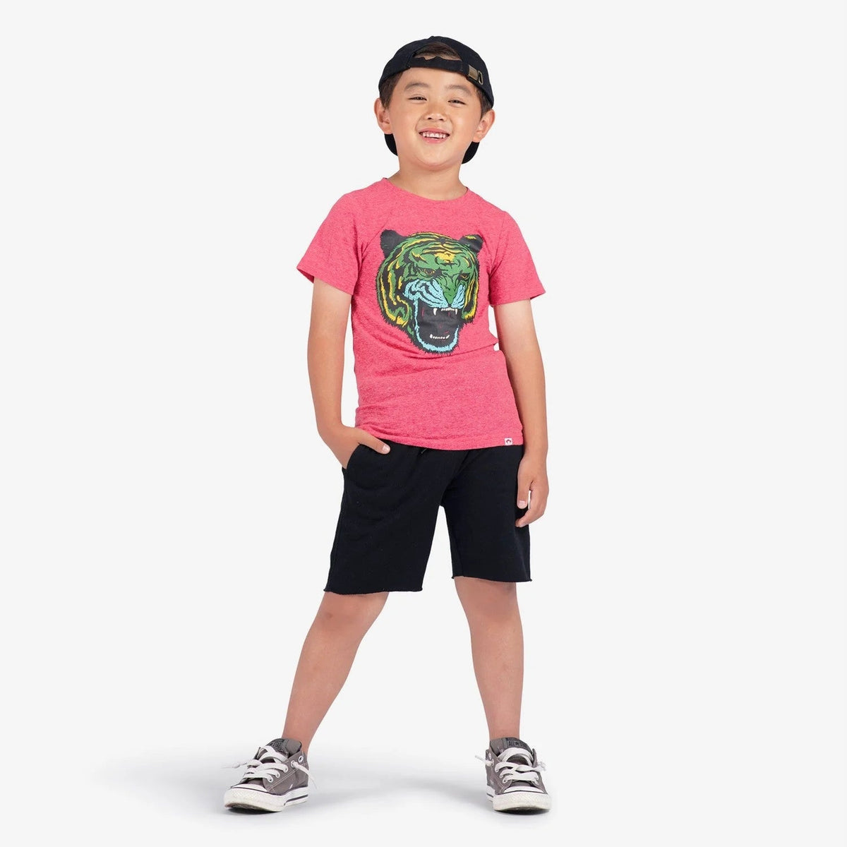 Child wearing a pink t-shirt with a tiger graphic and black shorts on a white background
