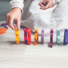 Colorful wooden blocks being arranged by a child's hand on a light surface.