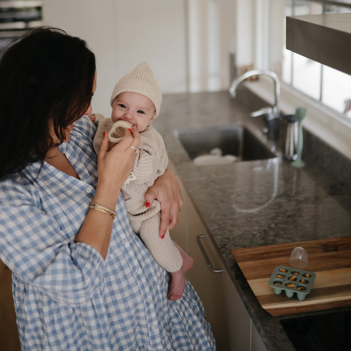 Woman holding a baby in a kitchen