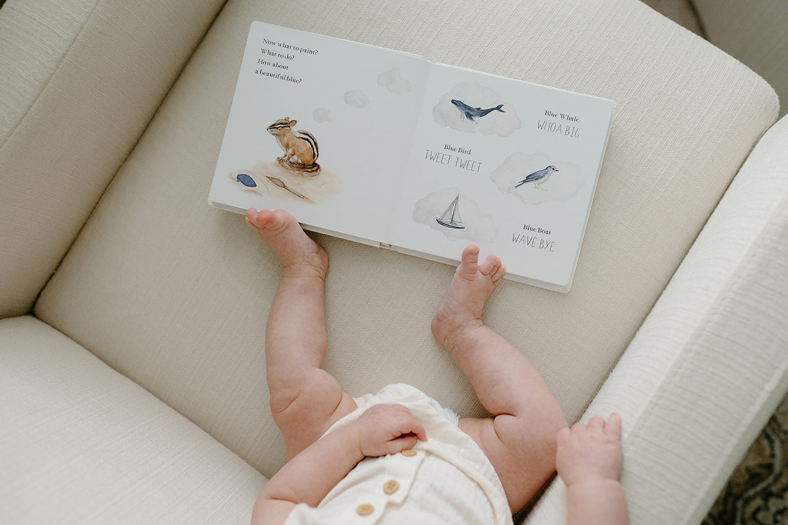 Baby reaching for a book on a couch