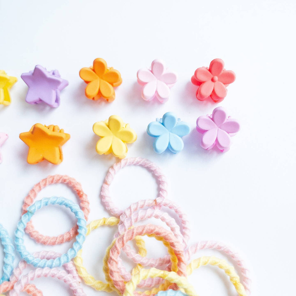 Colorful star and flower-shaped hair ties on a white background