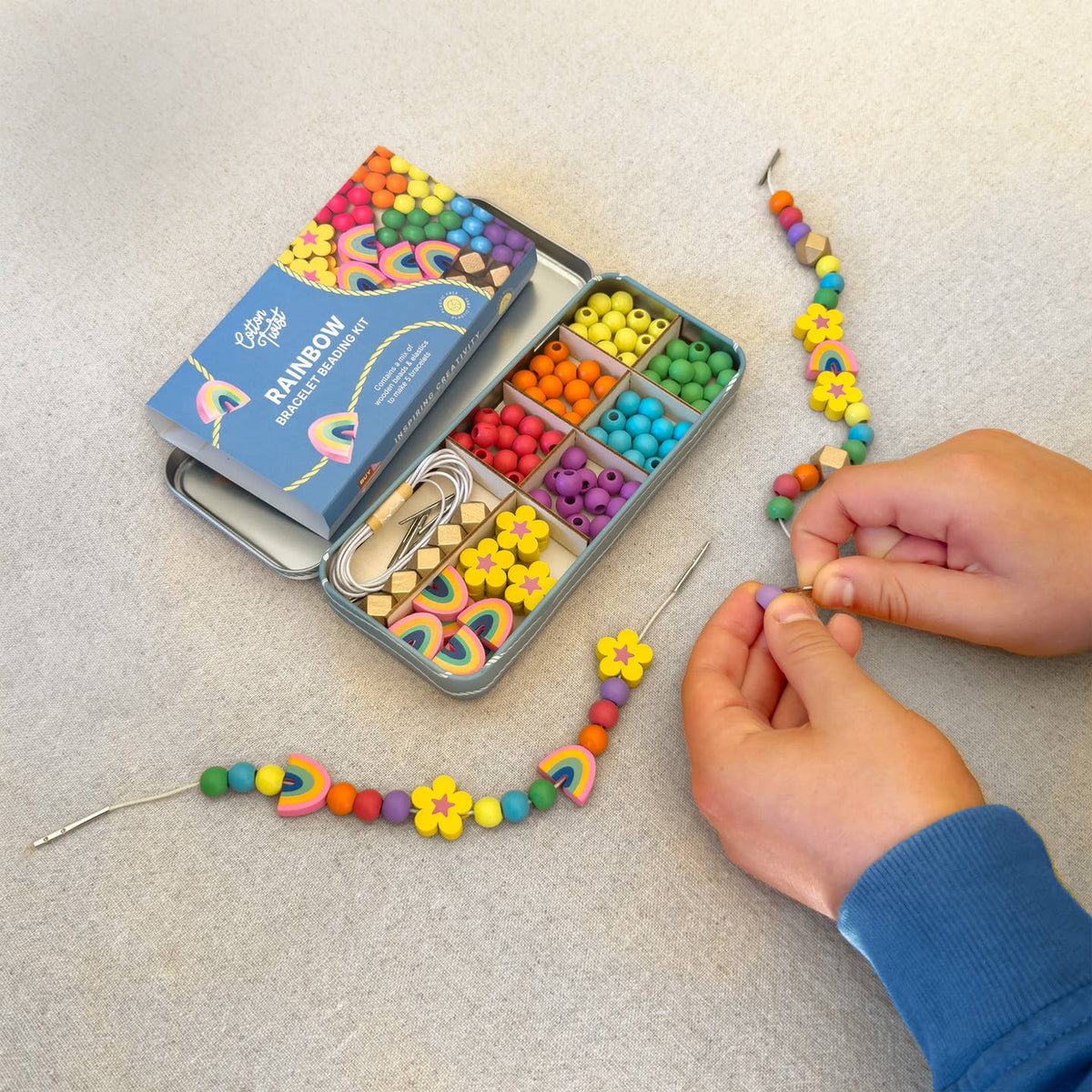 Colorful bead kit with beads and tools on a light surface