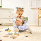 Child playing with colorful blocks on a carpeted floor in a room with furniture.