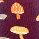 Close-up of a knit fabric with a burgundy background and a repeating mushroom pattern in orange, pale yellow, and light gray.