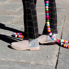 Close-up of feet wearing beige shoes with glittery soles on a stone pavement.