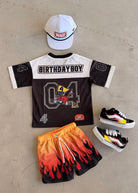 Children's birthday-themed outfit with shirt, shorts, and shoes on a neutral background