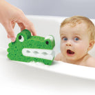Baby in a bathtub with a green frog-shaped bath toy