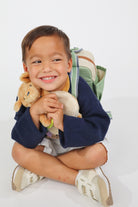 Child holding a teddy bear and smiling on a white background