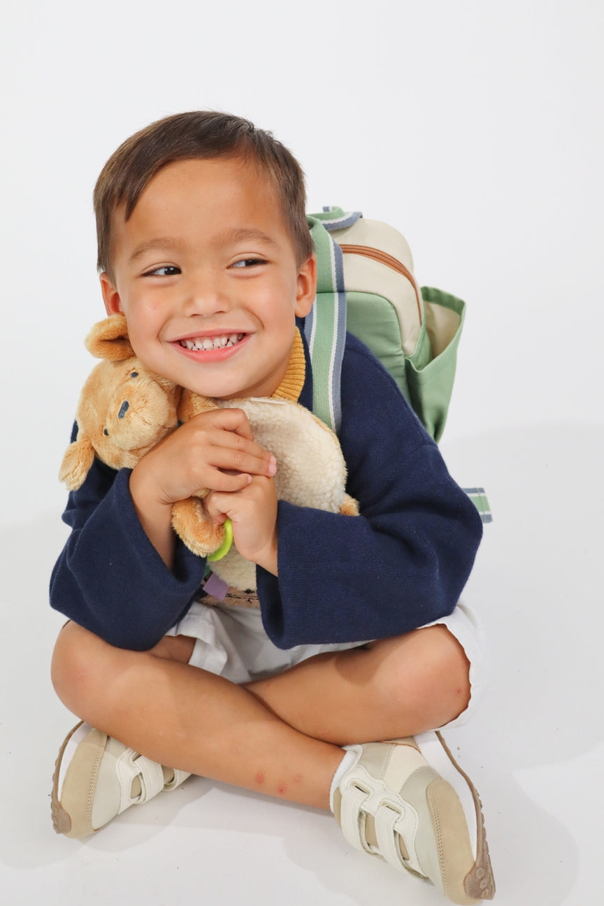 Child holding a teddy bear and smiling on a white background