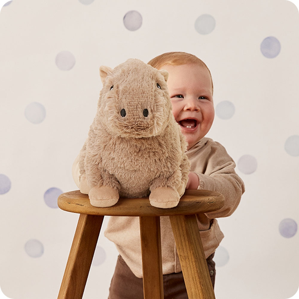 Child with a plush toy on a stool against a polka dot background