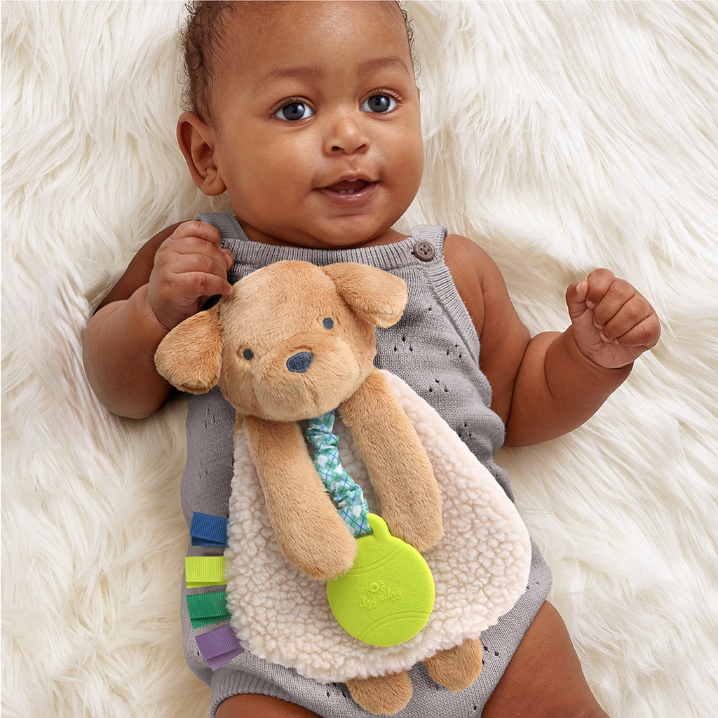 Baby holding a soft toy with colorful accents on a fluffy white surface