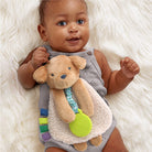 Baby holding a soft toy with colorful accents on a fluffy white surface