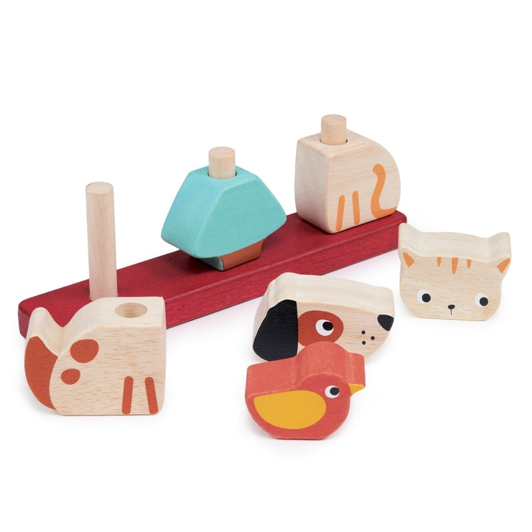Wooden Pet Stacker toy by Mentari featuring a red base with pegs, with a spotted red and white puppy body piece in the foreground, a blue and yellow bird piece, and a disassembled pastel blue block nearby against a plain white background.