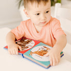 Child holding a book with animal illustrations on a light surface