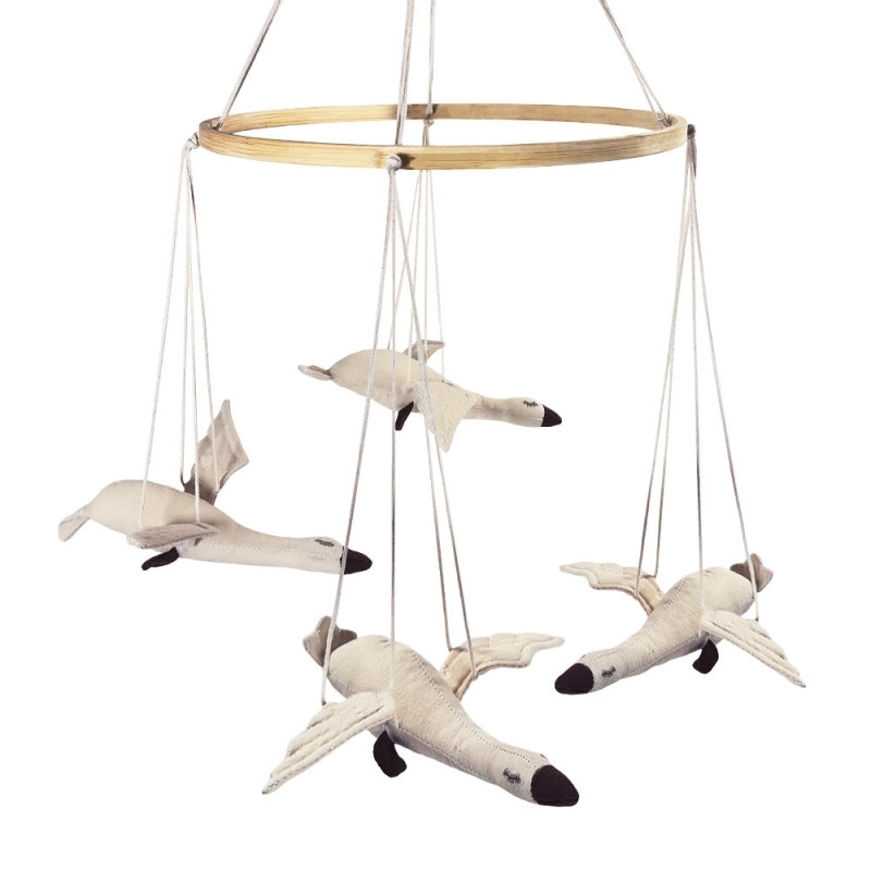 Wooden ring mobile with hanging toy swans on a white background