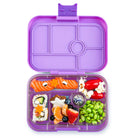 Purple bento box with compartments filled with various food items on a white background