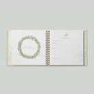 Open book with decorative wreath design on a light gray background