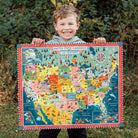 Child holding a colorful map of the United States and Canada outdoors.