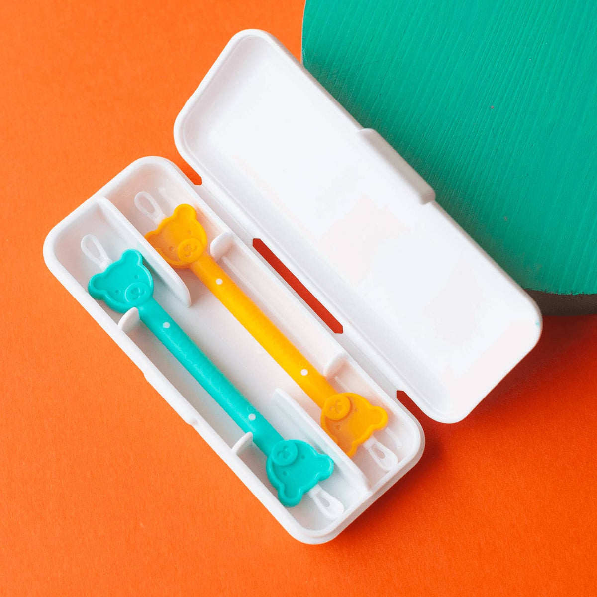 Colorful toothbrushes in a white case on an orange background