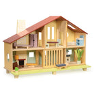 Wooden Cedar Chalet Modernist Dollhouse by Mentari featuring a mid-century modern architectural design with an open-front layout, a red gabled roof, a pebble-dash style chimney breast, and six furnished rooms complete with a starter set of modernist furniture and a sliding ground-floor grill opening onto an urban lawn with a potted plant and bench.