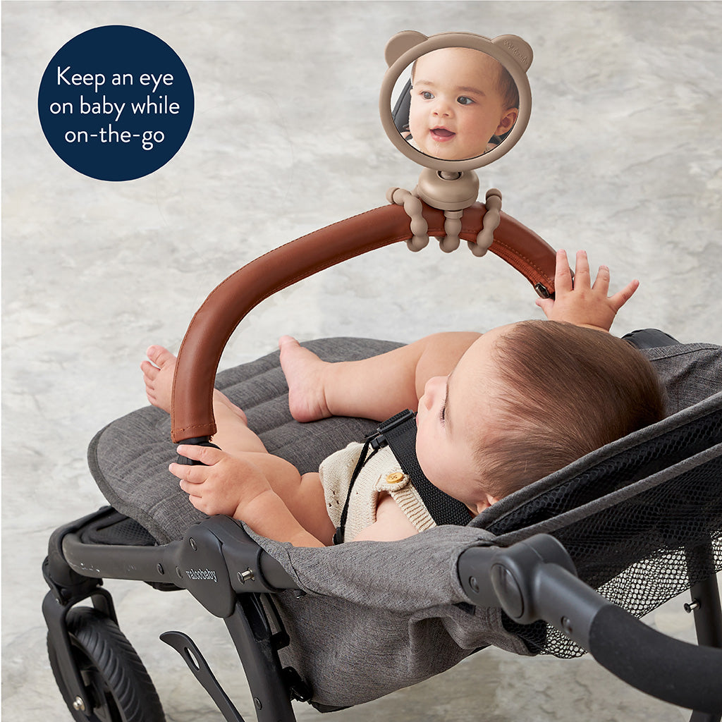 Baby in a stroller with a mirror attached, showing the baby's reflection.