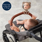 Baby in a stroller with a mirror attached, showing the baby's reflection.
