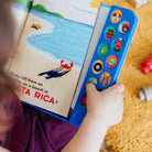 Child holding a colorful book with tactile elements and stickers.