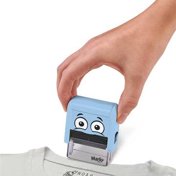 Hand using a blue stamp with a cartoon face on a white background