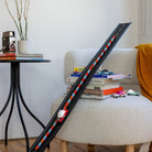 Model train track on a sofa with books and toy cars in a cozy living room setting.