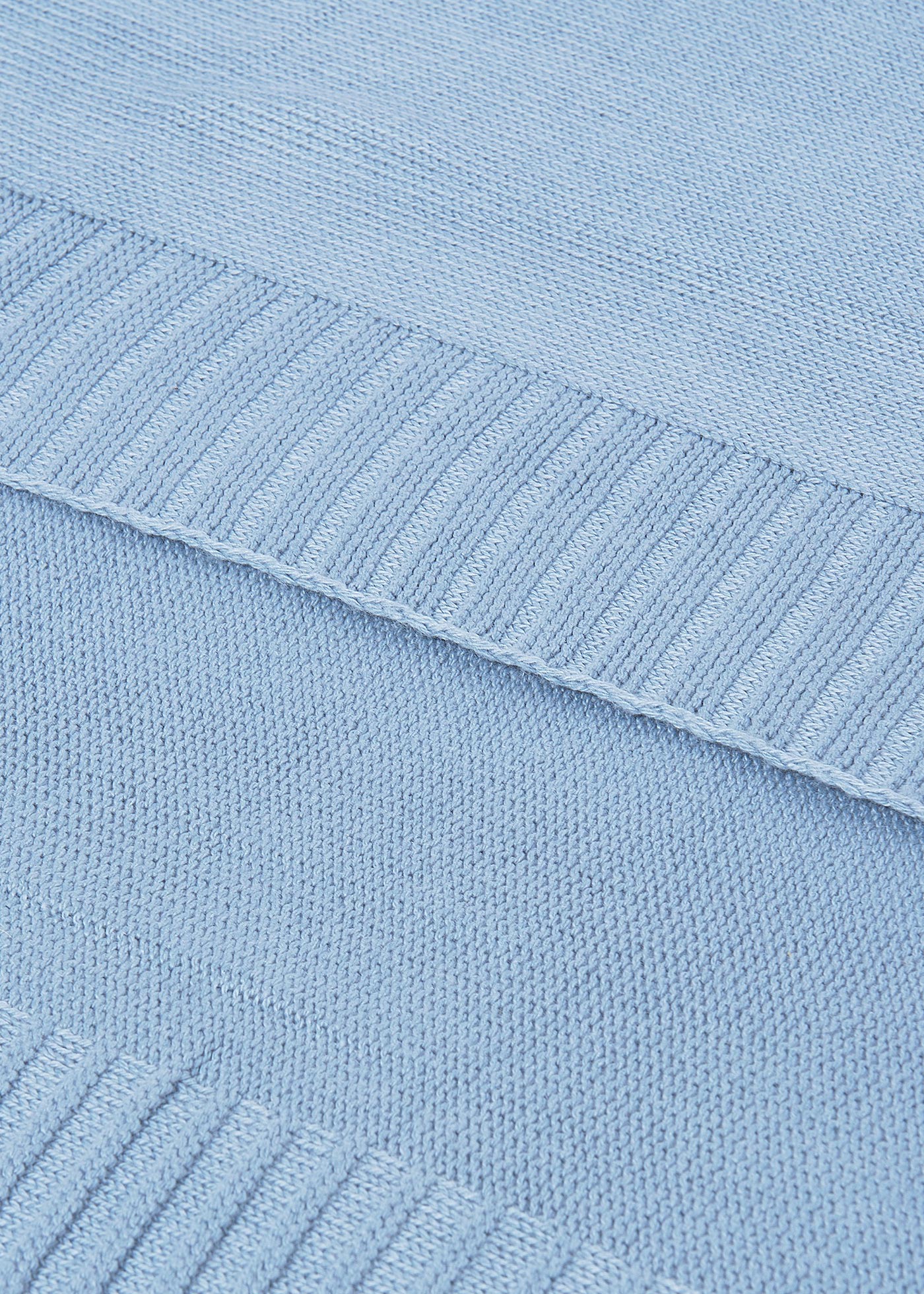 Close-up of a light blue knitted fabric with ribbed texture.