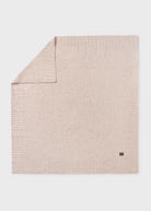 Beige textured blanket with a small logo on a light gray background