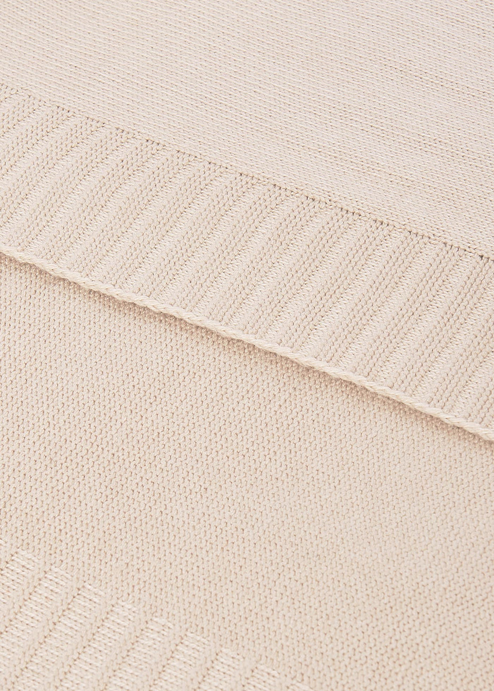 Close-up of a textured fabric with a ribbed edge on a light beige background