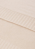 Close-up of a textured fabric with a ribbed edge on a light beige background