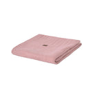 A folded dusty pink ribbed knit blanket with a small brown brand tag, isolated on a white background.