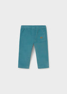A pair of teal corduroy pants for toddlers, shown from the back on a light gray background. The back features an elastic waistband, straight legs, and a single patch pocket on the right side with a small brown brand label.