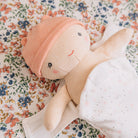Stuffed doll with a pink hat on a floral fabric background