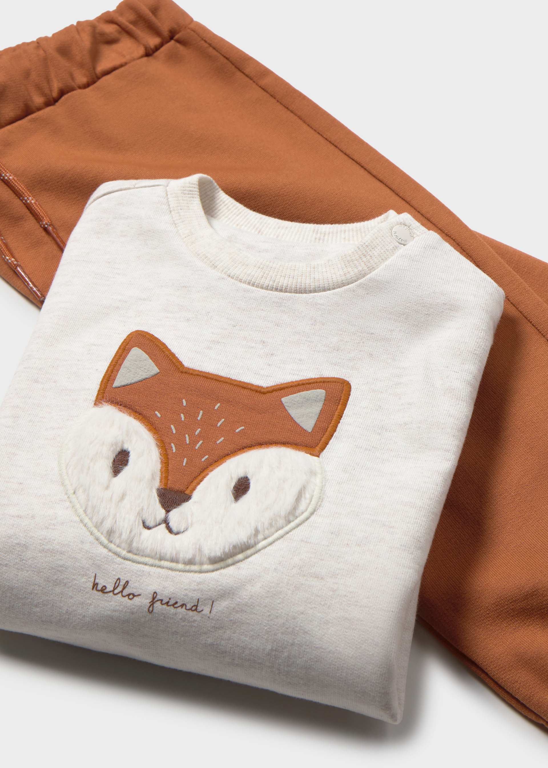 Folded white sweatshirt with a fox face design on a brown fabric background