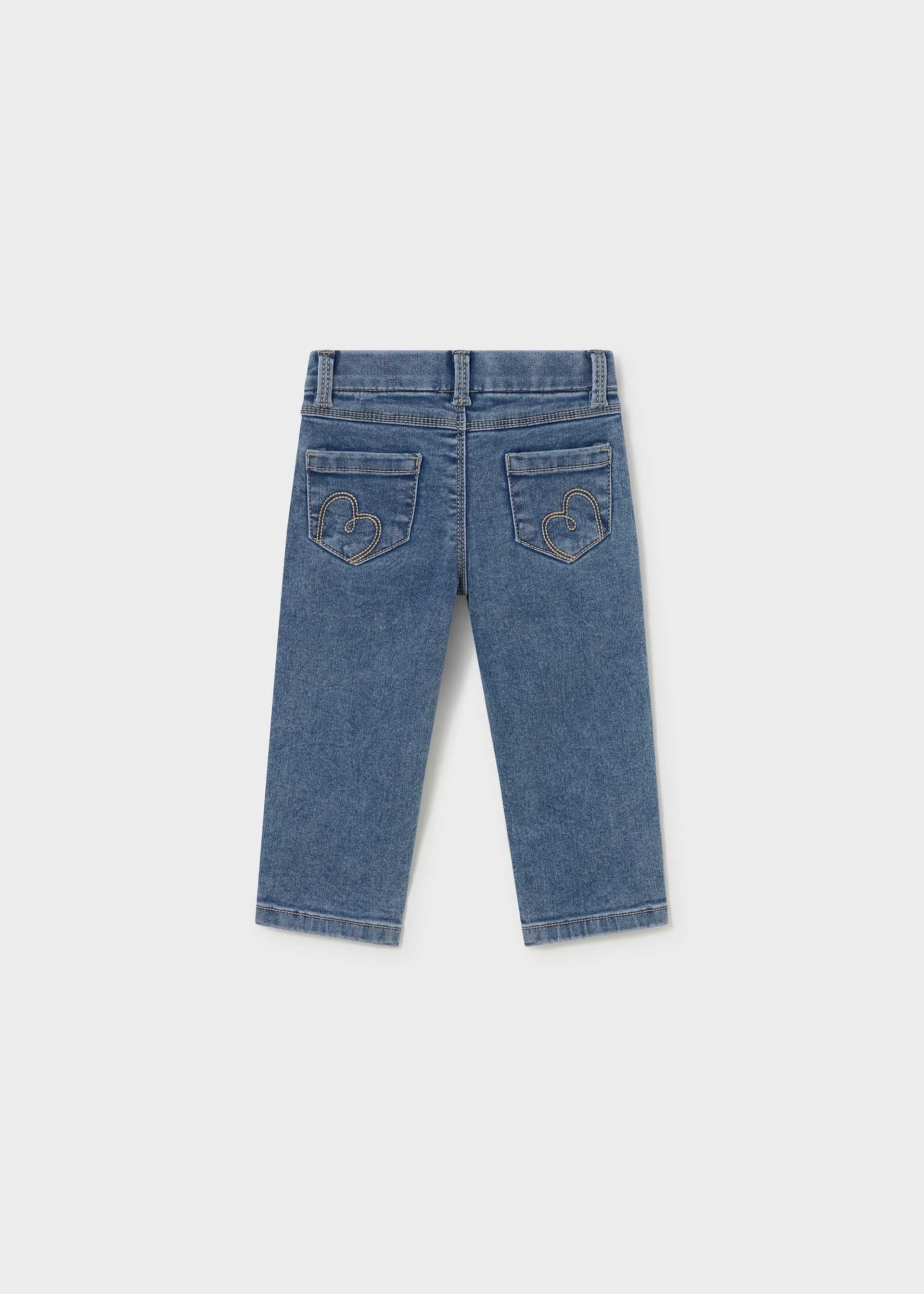 A pair of blue denim jeans shown from the back, featuring embroidered monogram details on the back pockets, displayed against a light gray background.
