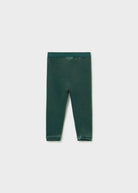 A pair of dark forest green leggings laid flat against a light gray background.