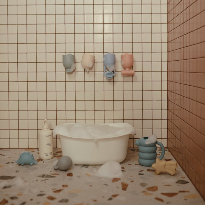 Bathroom scene with a bathtub, toys, and bath products against tiled walls.
