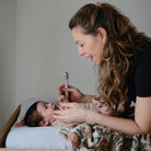 Woman holding a baby and using a smartphone in a home setting