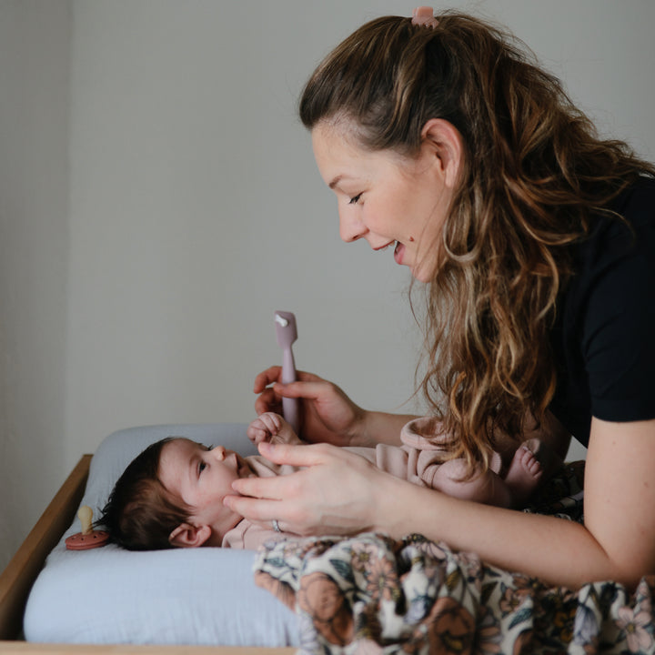 Woman holding a baby and using a smartphone in a home setting